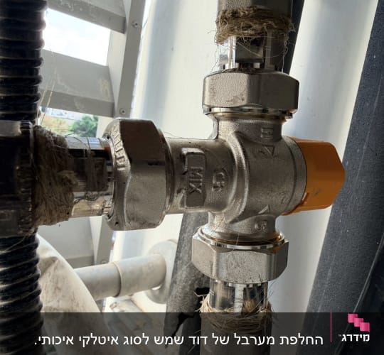 שסתום מתכת עם ידית כתומה בצנרת